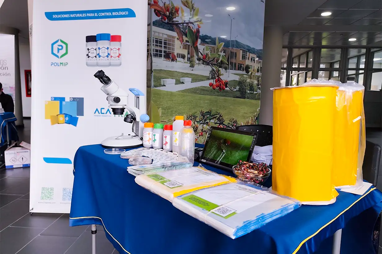Detalle del stand de ACAMIP con información sobre trampas y ácaros depredadores